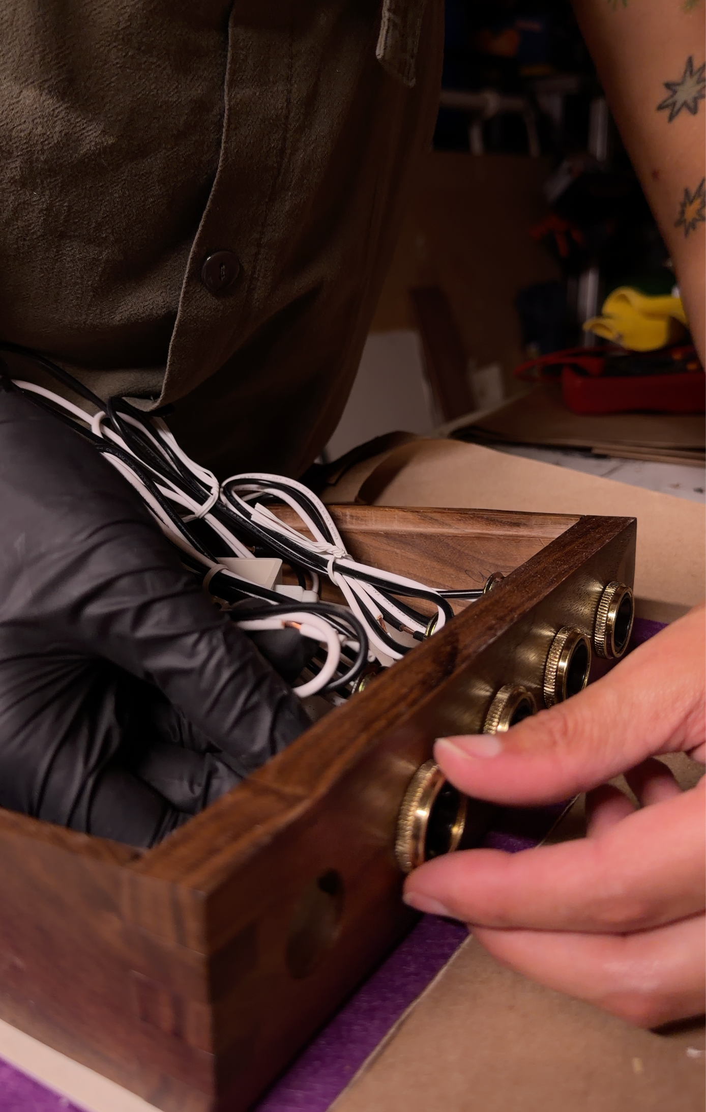 A close-up of a hand installing brass ring onto walnut lamp frame